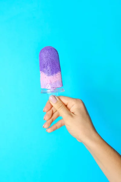Female hand with tasty blueberry ice cream on color background — Stock Photo, Image