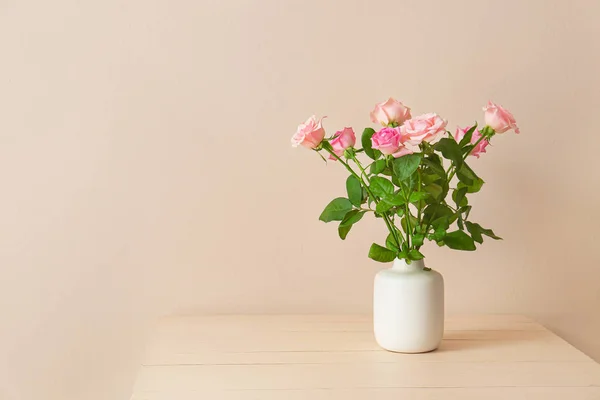 Beautiful rose flowers in vase on table against light background — Stok fotoğraf
