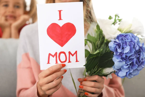 Hermosa joven con tarjeta de felicitación y flores de su hija en casa —  Fotos de Stock