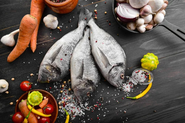 Raw dorado fish with products on dark wooden background