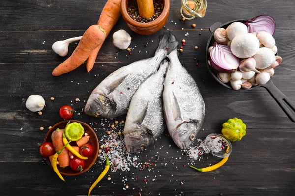 Syrové dorado ryby s produkty na tmavém dřevěném pozadí — Stock fotografie