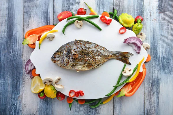 Board with prepared dorado fish and fresh vegetables on wooden table — Stock Photo, Image