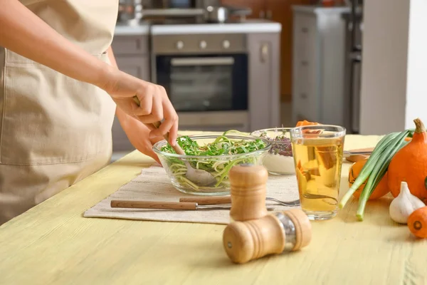 Kvinna som förbereder läckra grönsakssallad i köket — Stockfoto