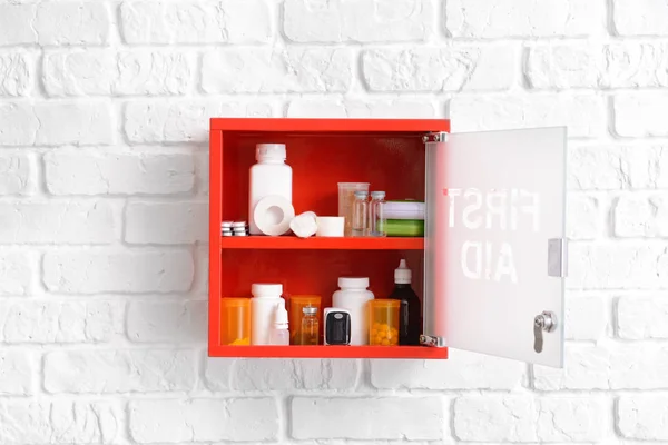 First aid kit hanging on white brick wall