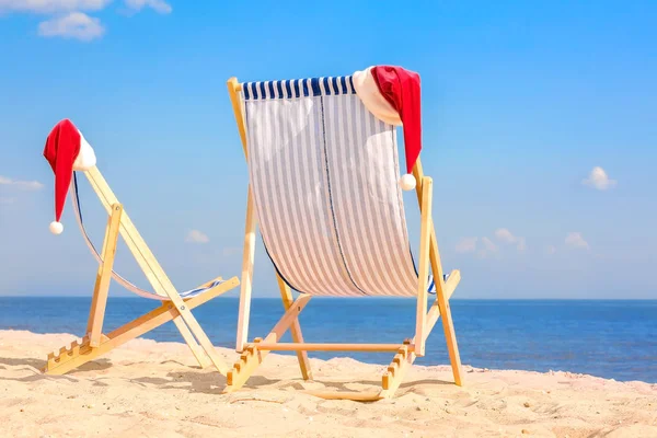 Sun loungers with Santa hats on sea beach — Stock Photo, Image