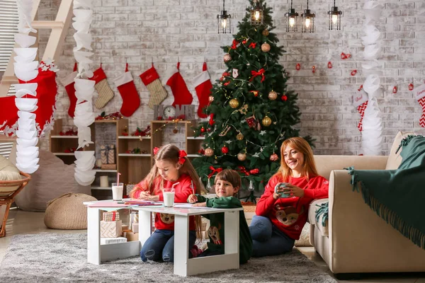 Crianças pequenas com a mãe na véspera de Natal em casa — Fotografia de Stock