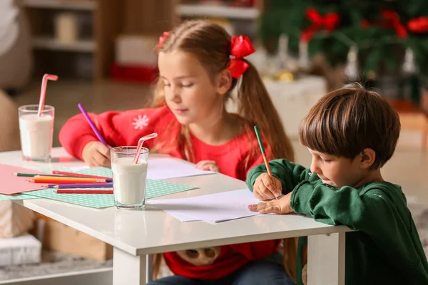 Маленькі діти пишуть листа Санті Клаусу вечором на Різдво. — стокове фото
