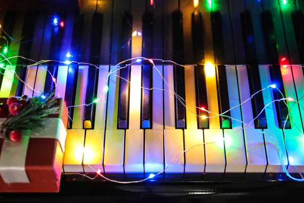 Teclado piano com luzes de Natal e caixa de presente — Fotografia de Stock