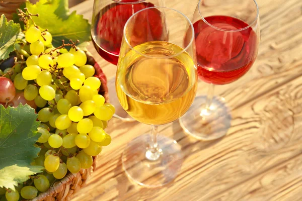 Bicchieri di vino saporito e uva su tavolo di legno — Foto Stock