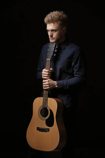 Handsome man with guitar on dark background — Stock Photo, Image