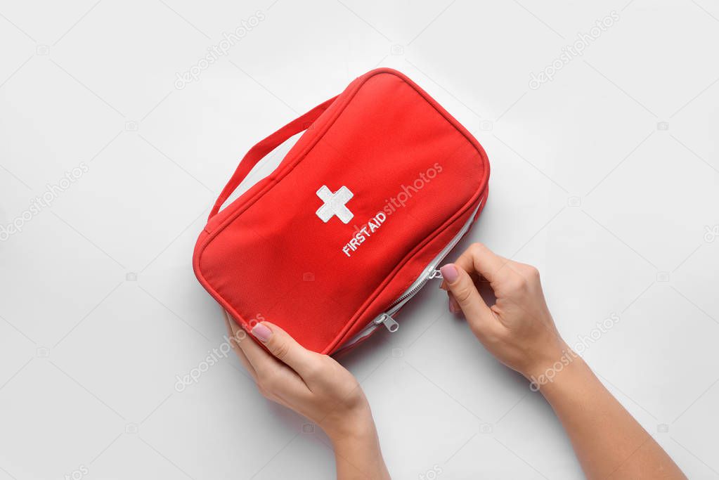 Female hands with first aid kit on white background