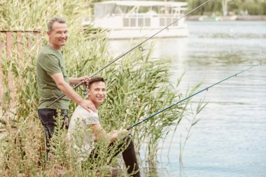 Genç adam ve babası nehirde balık tutuyor.
