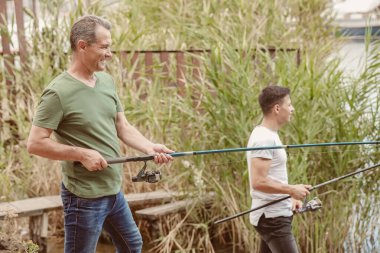 Genç adam ve babası nehirde balık tutuyor.