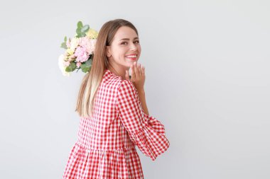 Hafif arka planda karanfil çiçek buketi ile güzel genç kadın