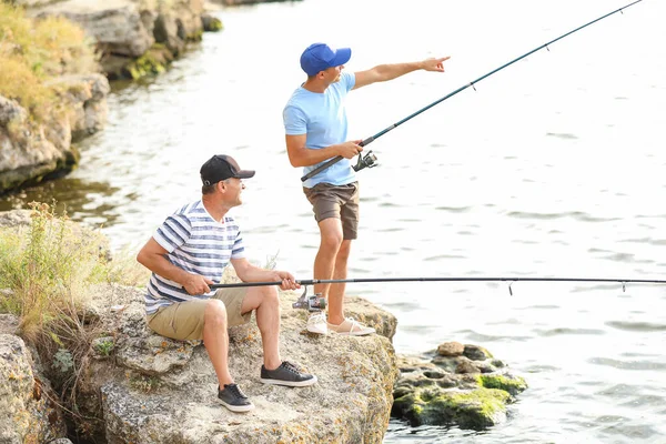 Mladý muž a jeho otec rybaří na řece — Stock fotografie