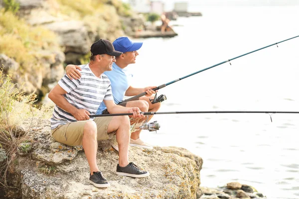 Giovane uomo e suo padre pesca sul fiume — Foto Stock