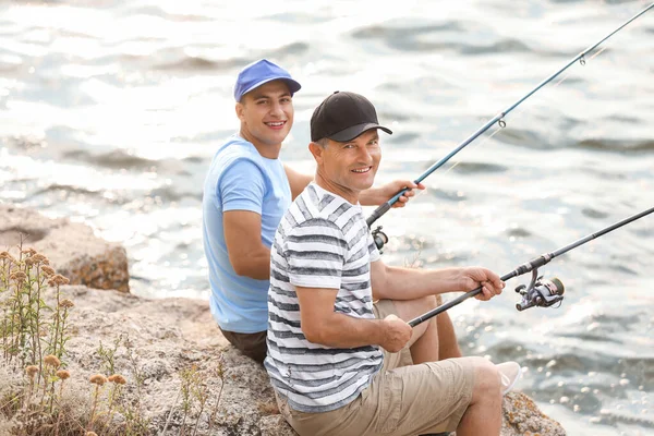 Giovane uomo e suo padre pesca sul fiume — Foto Stock