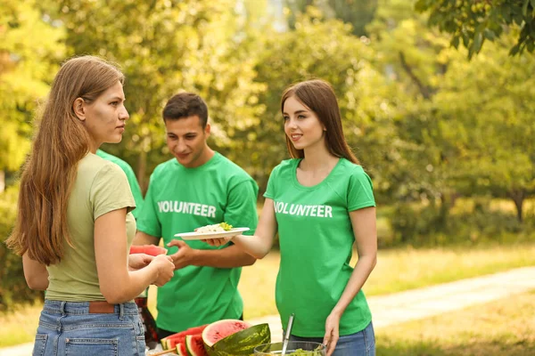 Młodzi wolontariusze dający żywność biednym ludziom na świeżym powietrzu — Zdjęcie stockowe