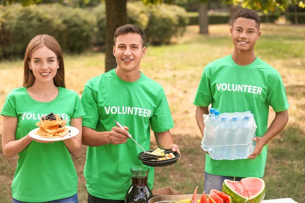 Young volunteers with food for poor people outdoors — Stock Photo, Image