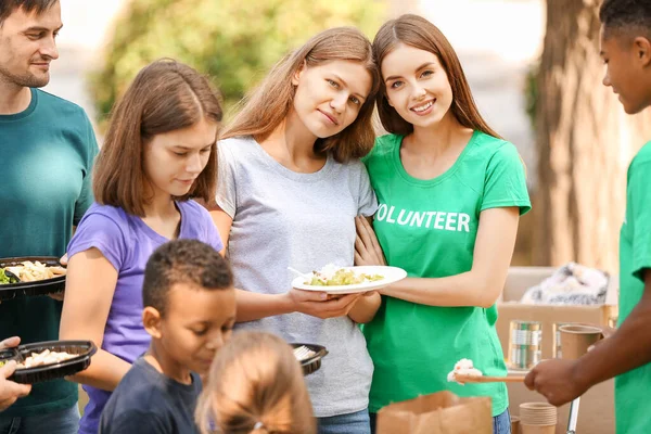 Jóvenes voluntarios dando comida a los pobres al aire libre — Foto de Stock