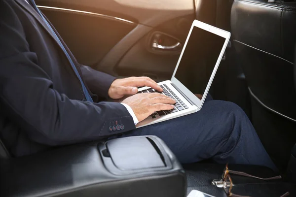 Erfolgreicher Geschäftsmann mit Laptop im modernen Auto — Stockfoto