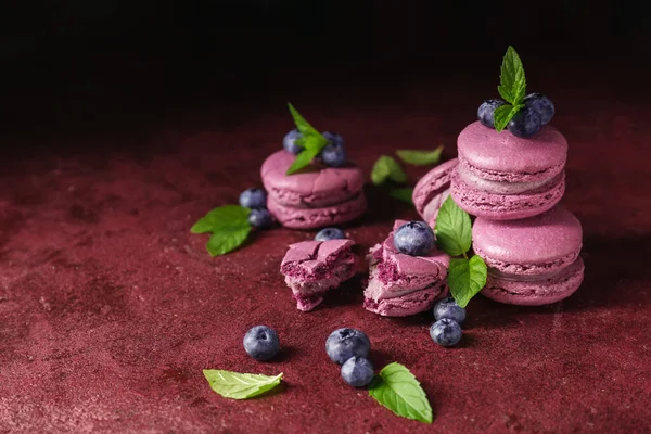 Sabrosos macarrones de arándanos con menta sobre fondo de color — Foto de Stock