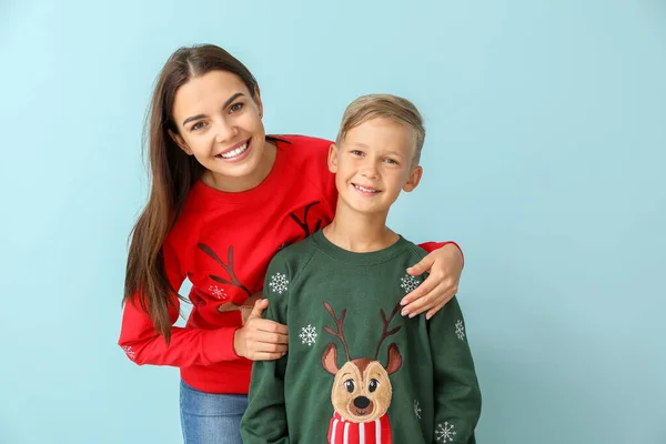 Little boy and his mother in Christmas sweaters on color background — Stock Photo, Image