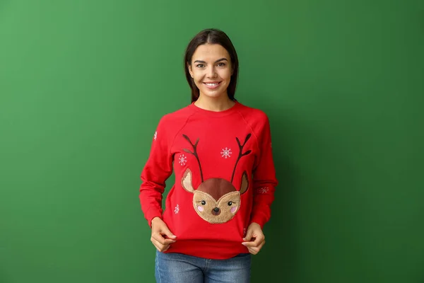 Young woman in Christmas sweater on color background — Stock Photo, Image