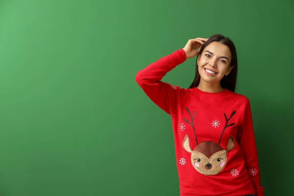 Jonge vrouw in Kerst trui op kleur achtergrond — Stockfoto