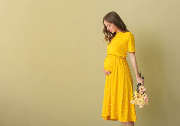 Mooie zwangere vrouw met boeket bloemen op kleur achtergrond — Stockfoto