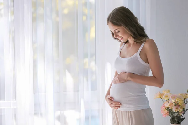 Beautiful pregnant woman near window at home — Stock Photo, Image