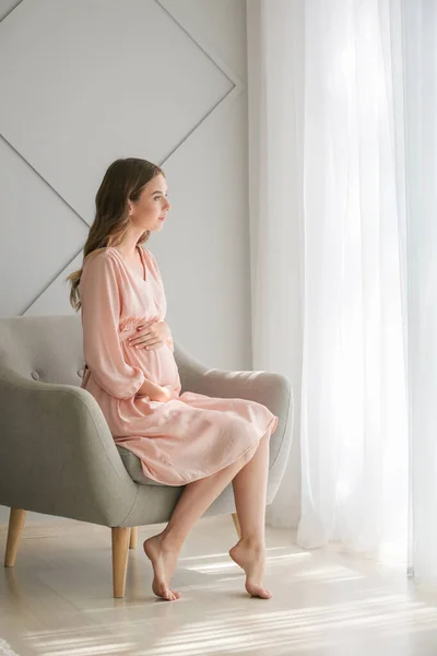 Красивая беременная женщина сидит в кресле дома — стоковое фото