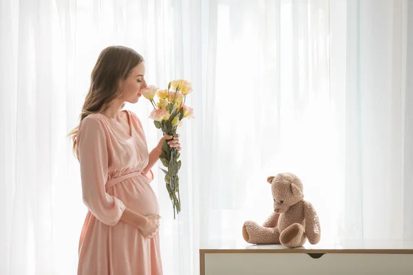 窓の近くに花を持つ美しい妊娠中の女性 — ストック写真