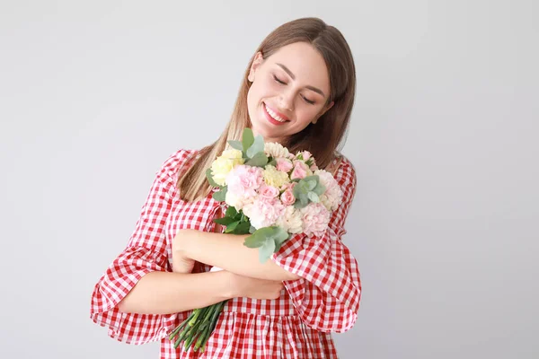 Vacker ung kvinna med bukett av nejlika blommor på ljus bakgrund — Stockfoto