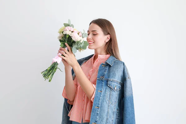 Beautiful young woman with bouquet of carnation flowers on light background — Stock Photo, Image