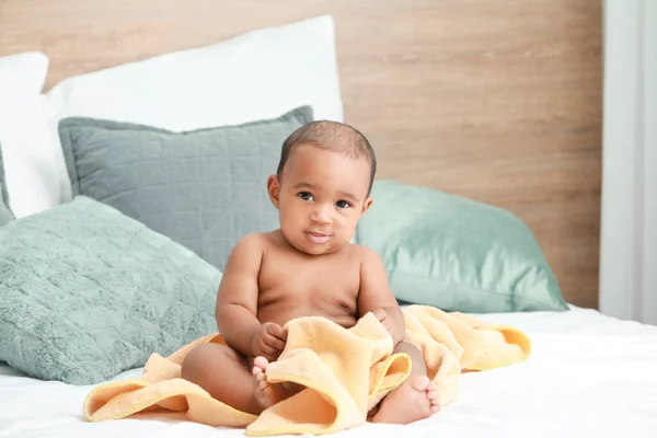 Süßes afrikanisch-amerikanisches Baby mit weichem Handtuch auf dem Bett zu Hause — Stockfoto