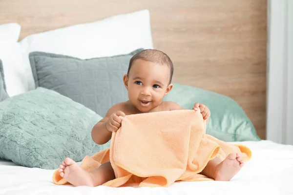 Милый афроамериканец с мягким полотенцем на кровати дома — стоковое фото