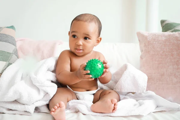 自宅でベッドの上に柔らかいタオルとおもちゃでかわいいアフリカ系アメリカ人の赤ちゃん — ストック写真
