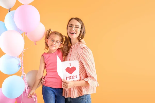 Little girl greeting her mother on color background — Stock Photo, Image