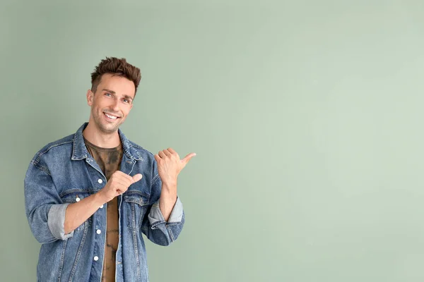 Handsome young man showing something on color background