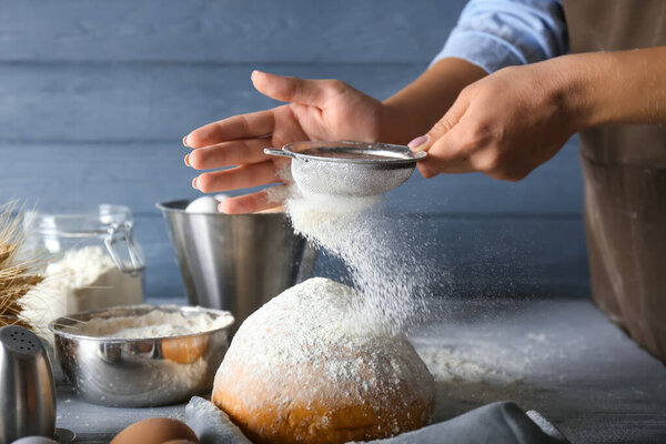 Woman sieving flour in kitchen