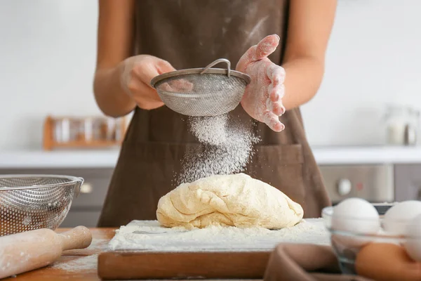 Mulher peneirando farinha na cozinha — Fotografia de Stock