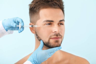 Yakışıklı adam renk arka plan üzerinde dolgu enjeksiyonu alan