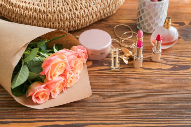 Masanın üzerinde makyaj malzemesi olan gül çiçekleri.