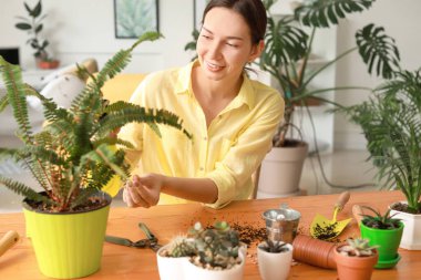 Evde çiçeklerle ilgilenen genç bir kadın.