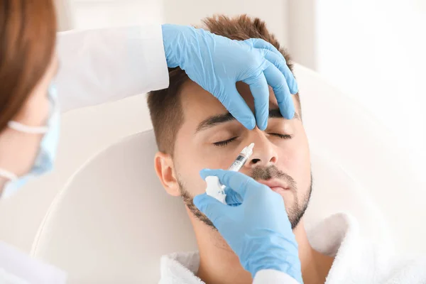 Handsome man receiving filler injection in beauty salon — Stock Photo, Image