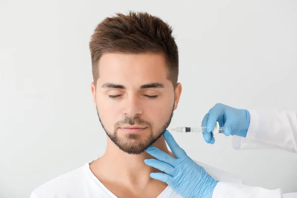 Handsome man receiving filler injection on grey background — Stock Photo, Image