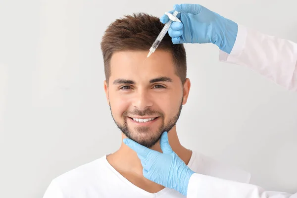 Bonito homem recebendo injeção de enchimento em fundo cinza — Fotografia de Stock