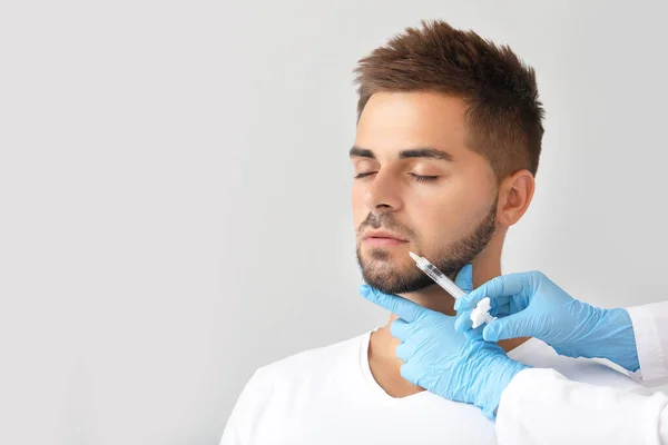 Schöner Mann erhält Spritze auf grauem Hintergrund — Stockfoto