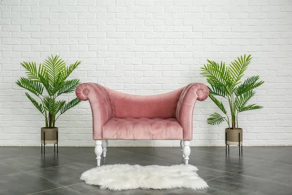 Comfortable sofa and houseplants near white brick wall — Stock Photo, Image